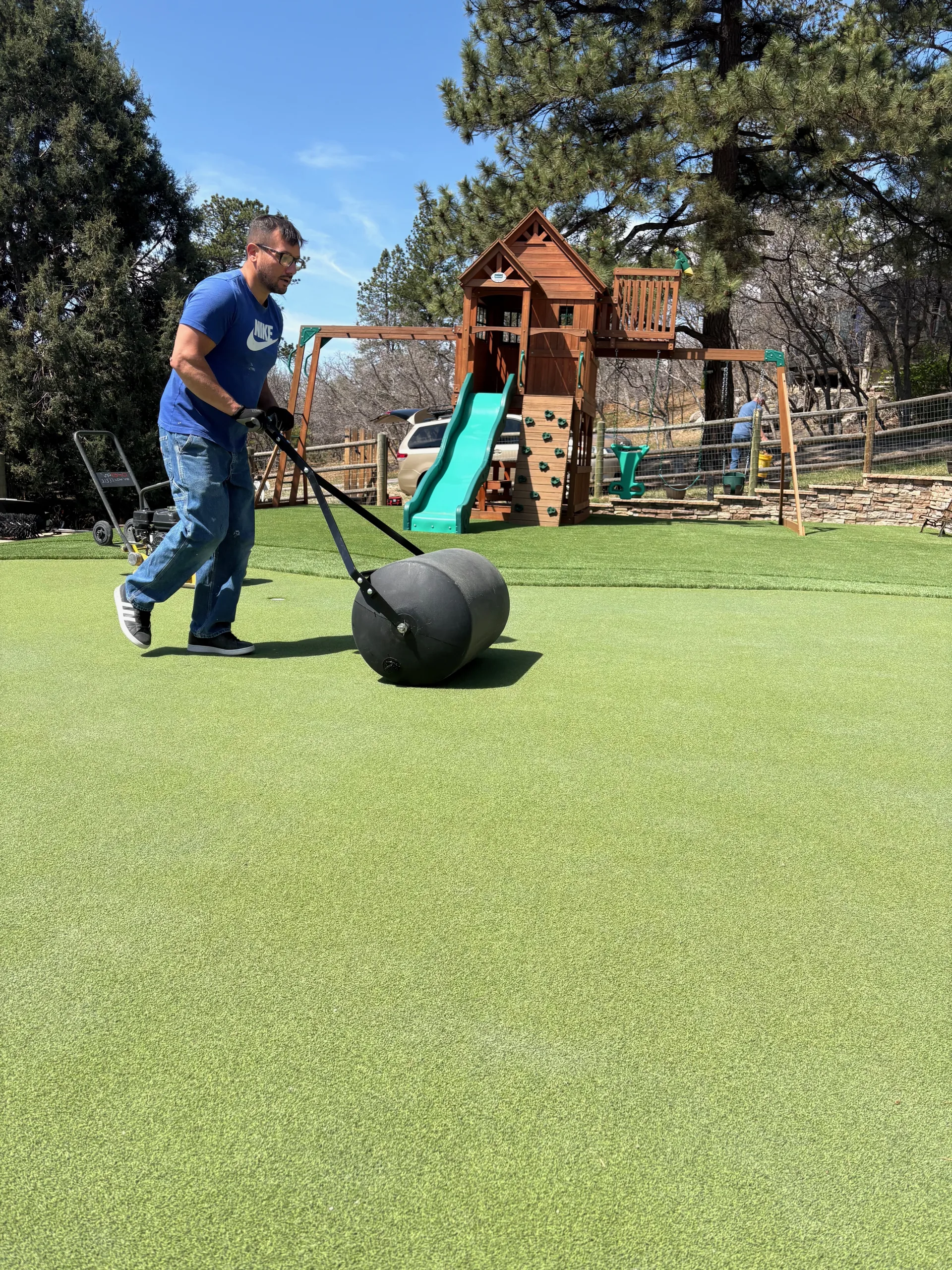 Technician rolling a putting green with a steel roller for compaction